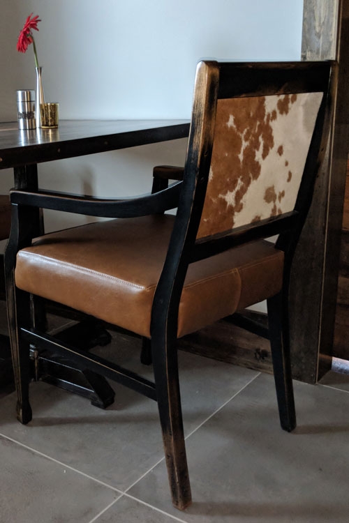 Downstairs & Upstairs Dining Rooms: Chairs with a custom-distressed finish, leather-look vinyl seats, and hair-on-hide leather backs
